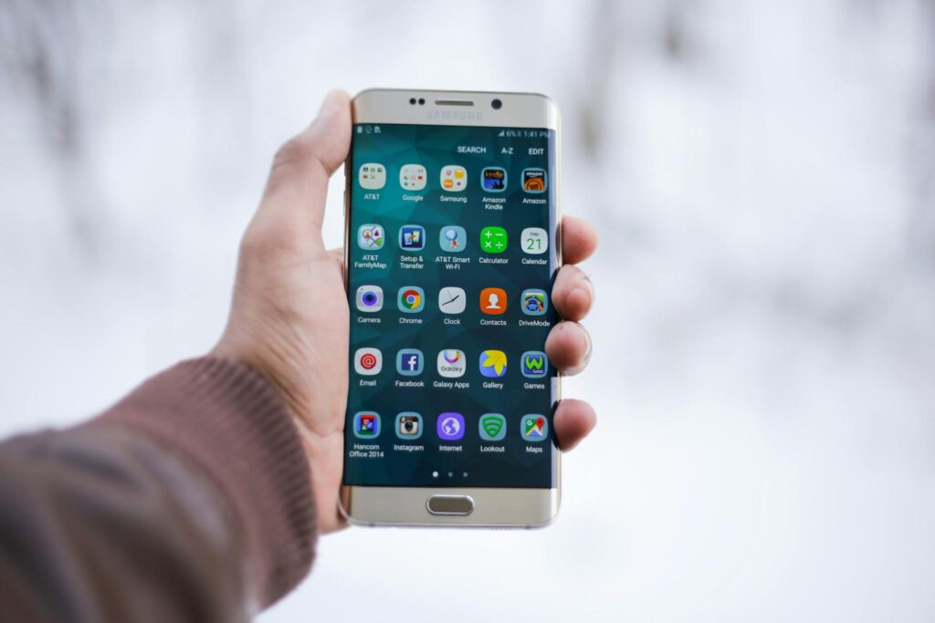 Nahaufnahme einer Hand, die ein Samsung-Smartphone hält, auf dem verschiedene App-Symbole angezeigt werden