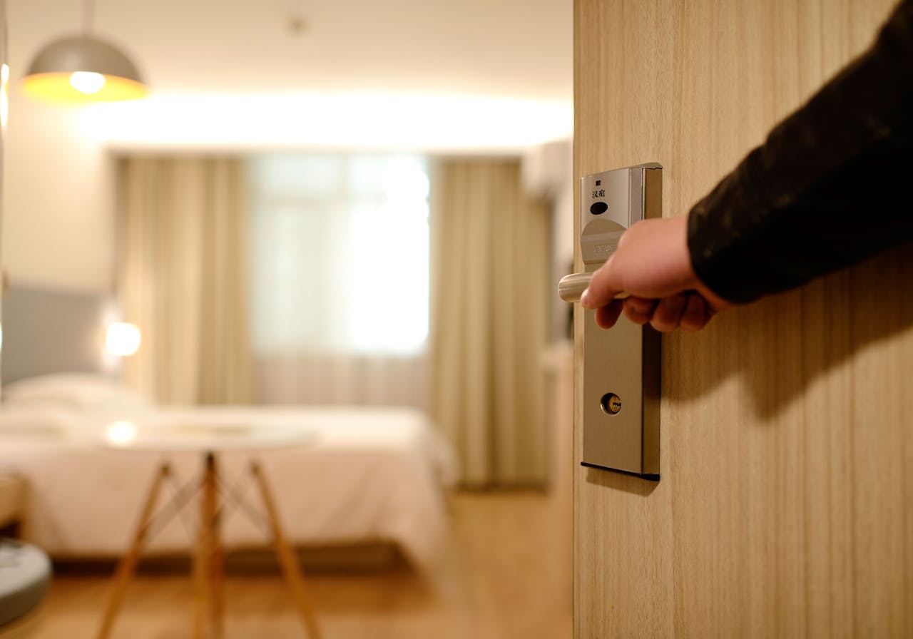 Eine Hand öffnet die Tür zu einem modernen Hotelzimmer mit elektronischem Schloss
