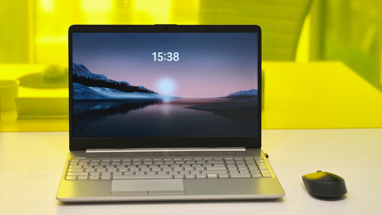 Blog erstellen als Anfänger (03.12.2025) Ein silberner Laptop und eine Maus auf einem weißen Schreibtisch, davor ein Bildschirm mit Landschaftsbild und gelbem Hintergrund. Das Bild symbolisiert, dass das Blog erstellen als Anfänger wirklich möglich ist