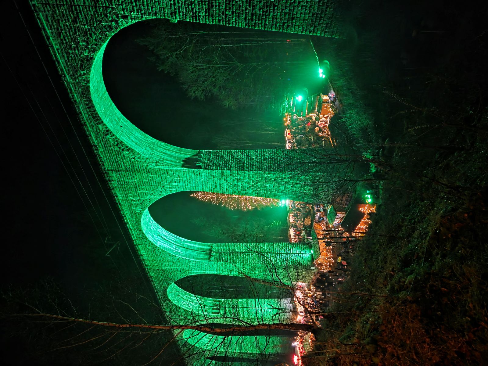 Grün beleuchteter Weihnachtsmarkt Ravennaschlucht bei Nacht.