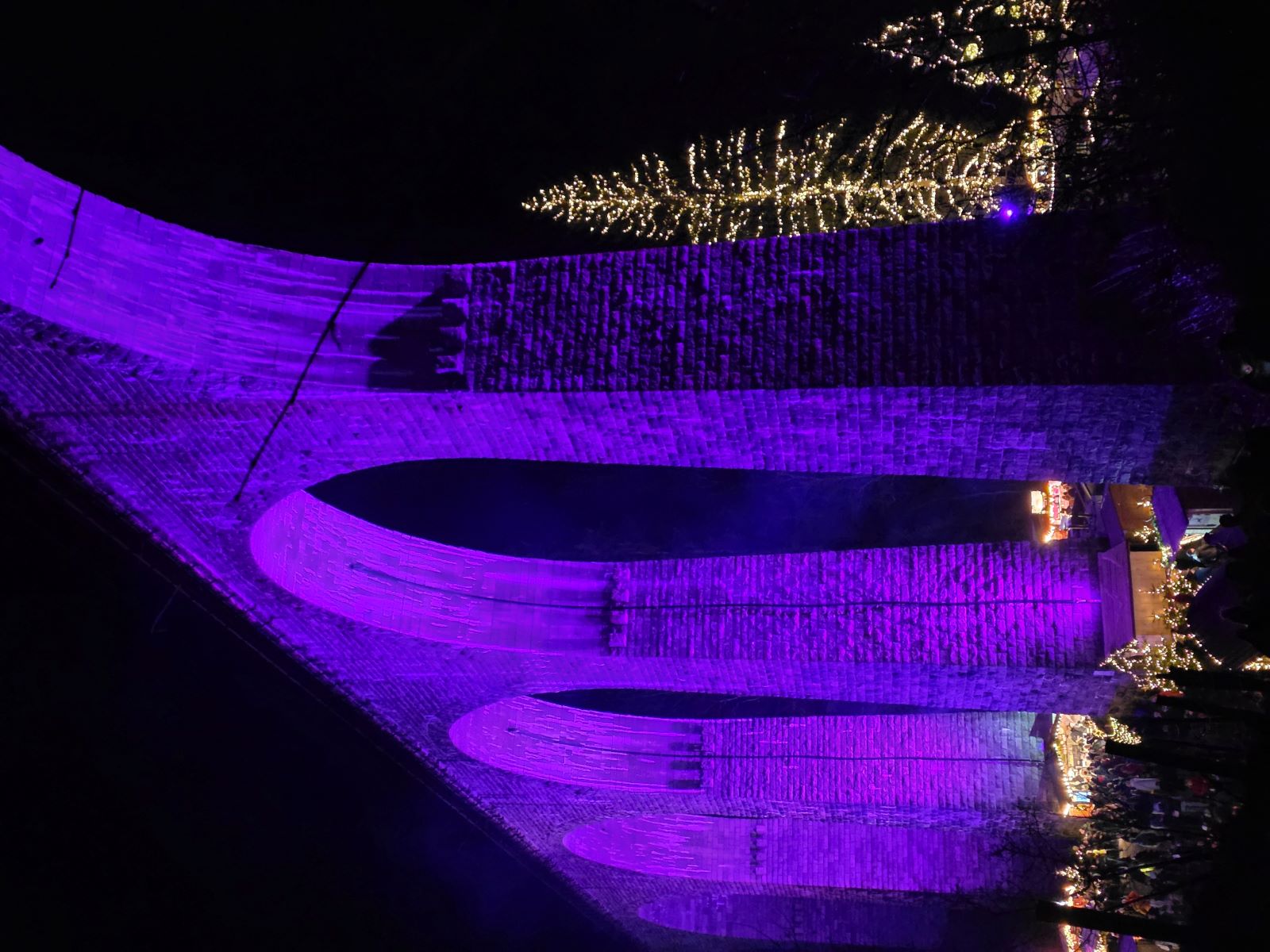 Lila beleuchteter Weihnachtsmarkt in der Ravennaschlucht bei Nacht.