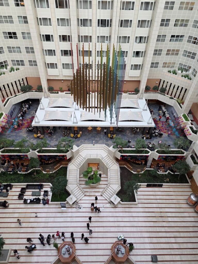 Silvester in Prag (04.01.2026) das Atrium des Hilton Hotelgebäudes mit mehreren Etagen, einer zentralen Treppe und einer großen, hängenden Skulptur