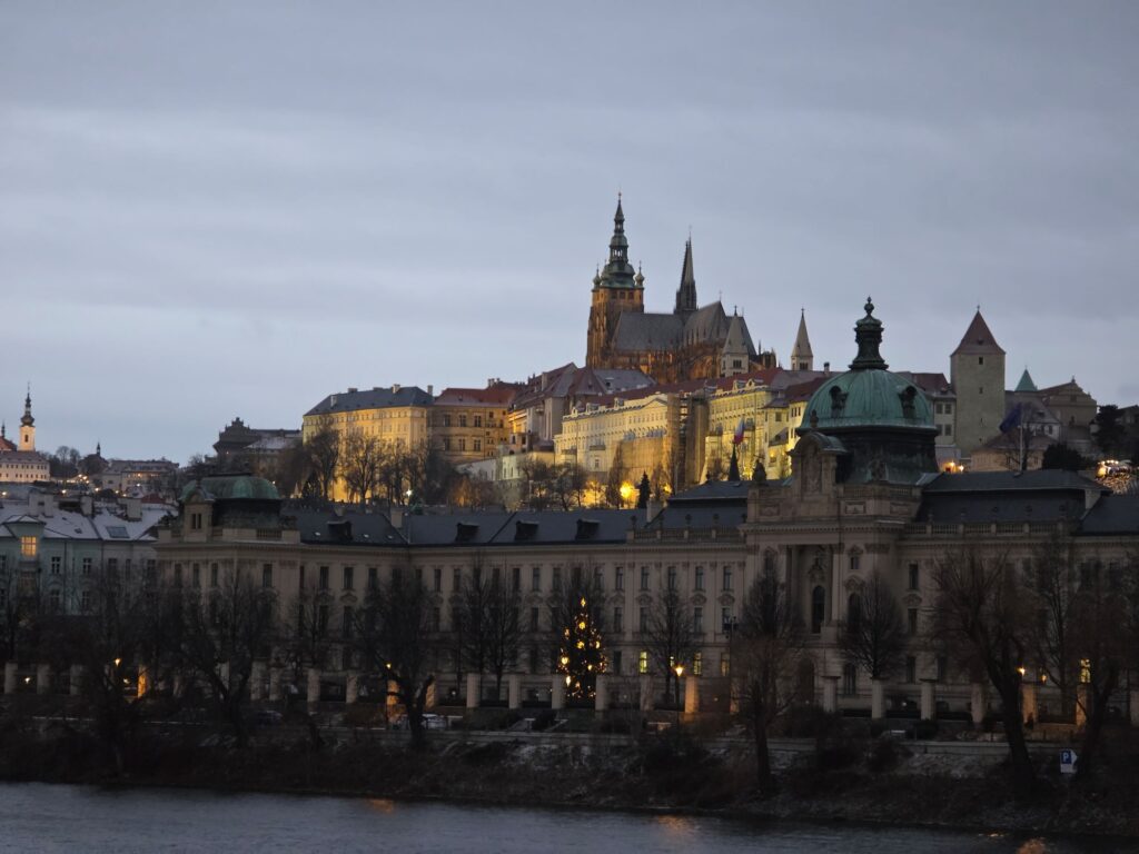 Silvester in Prag (04.01.2026) bebaute Uferlandschaft am Abend mit der Prager Burg auf einem Hügel im Hintergrund