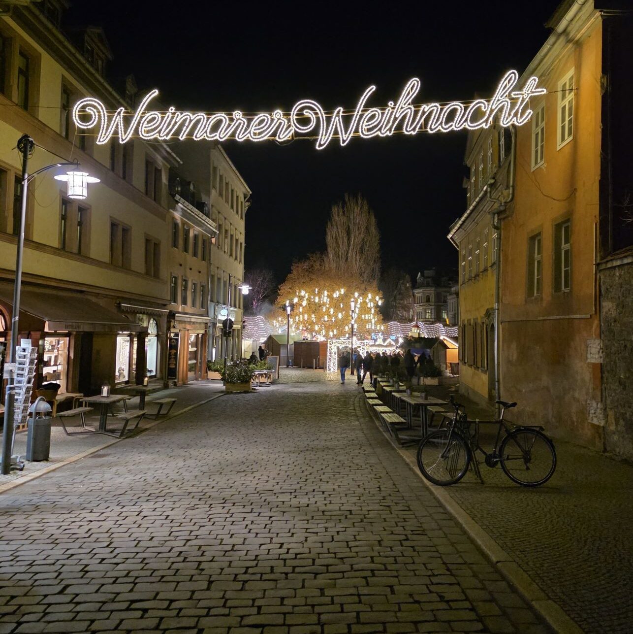 Silvester in Prag (04.01.2026) eine gepflasterte Gasse mit historischen Gebäuden und der Leuchtschrift „Weimarer Weihnacht“ bei Nacht