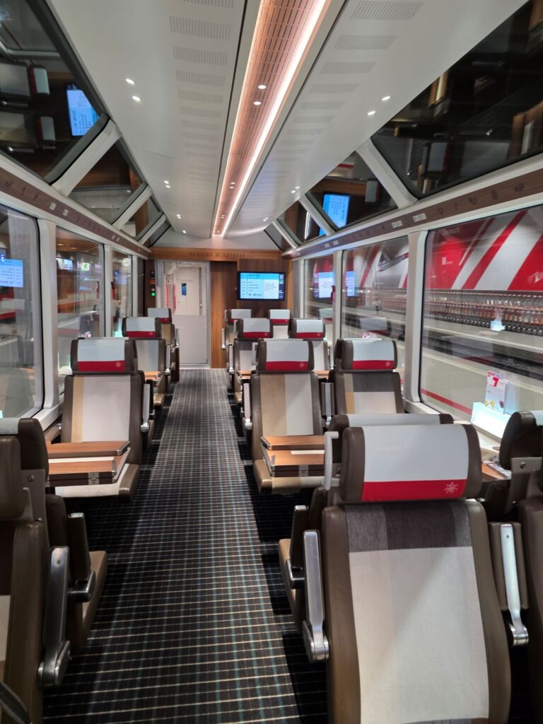 Glacier Express (01.02.2026) Innenansicht eines Zugabteil im Glacier Express, Zweier- und Vierersitze mit Holztischen
