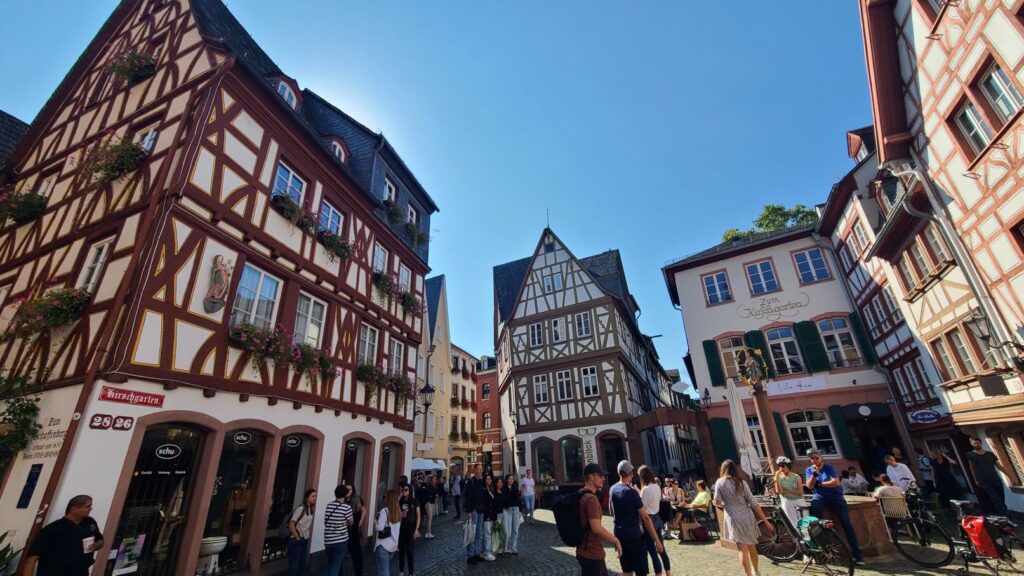 Stadtabenteuerspiel Mainz (13.02.2026) Viele ältere Häuser in der Mainzer Altstadt mit engen Gassen und vielen Menschen bei wolkenlosen blauen Himmel